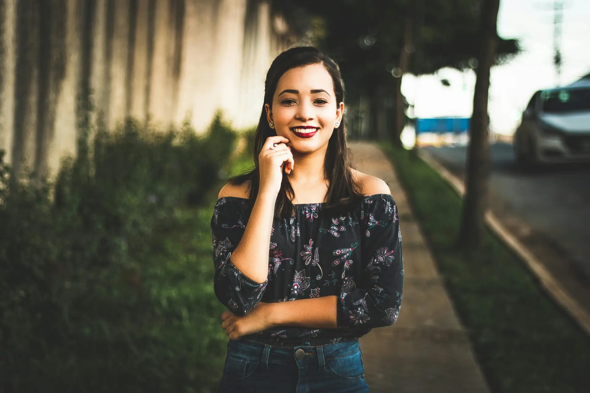 Smiling woman in casual wear posing confidently on a sunny city street.
